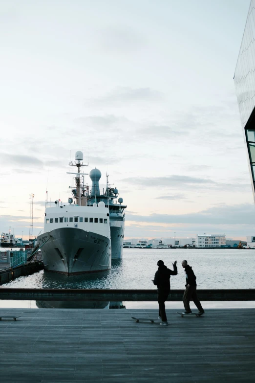 a couple of people that are standing in front of a boat, by Jens Søndergaard, happening, military buildings, reykjavik, humans exploring, looking at spaceships at dock