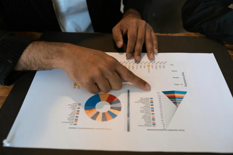 a close up of a person pointing at a piece of paper, pexels contest winner, analytical art, bar charts, colour print, 2070, round-cropped