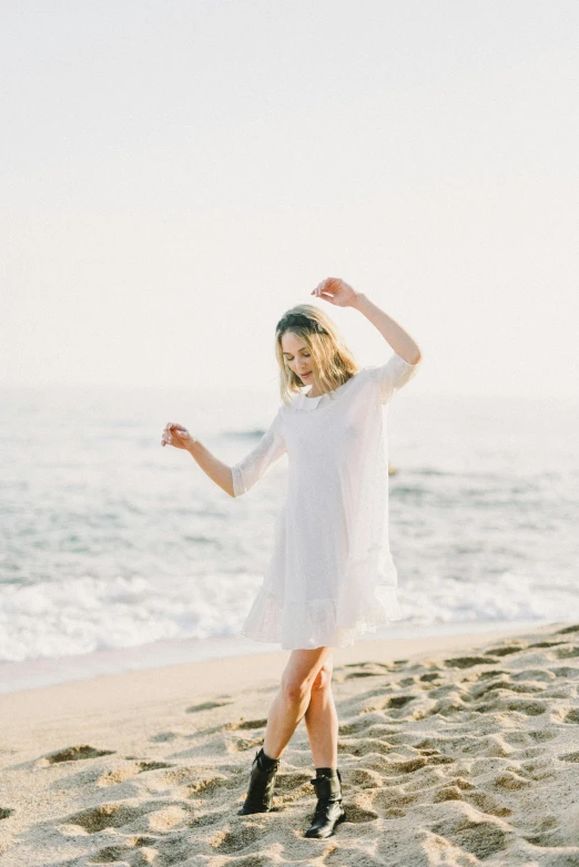 a woman standing on top of a sandy beach, gauze angel dress, sydney sweeney, white sleeves, full product shot