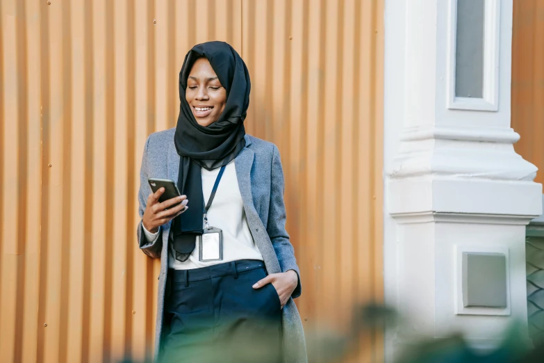 a woman in a hijab looking at her cell phone, trending on pexels, girl in a suit, wearing a dark shirt and jeans, somali woman, swedish