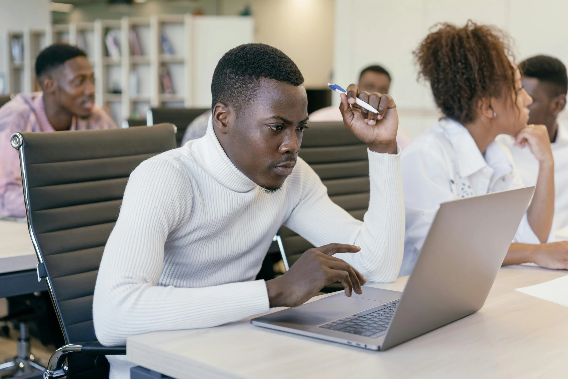 a group of people sitting around a table with laptops, trending on pexels, east african man with curly hair, concentration, thumbnail, background image