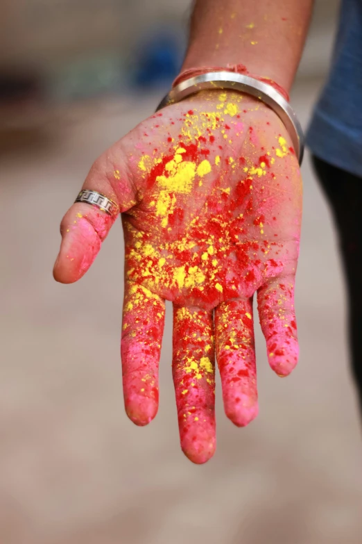 a person with yellow and red paint on their hands, spatter, vibrantly lush, handheld, with colourful intricate