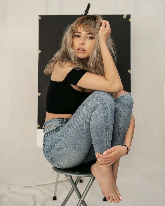 a woman sitting on top of a chair, inspired by Jean Hey, trending on pexels, portrait sophie mudd, ( ( ( wearing jeans ) ) ), gray canvas, non binary model