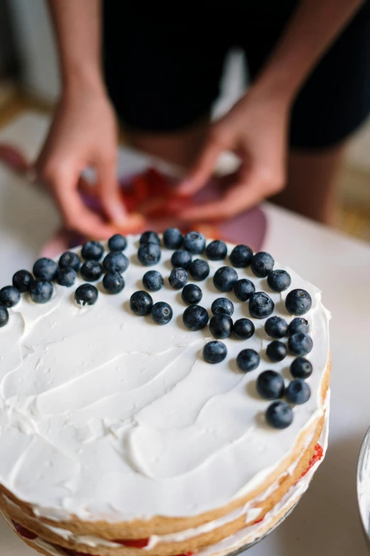 a close up of a cake on a table, inspired by Christen Købke, trending on unsplash, wearing a blue berries, baking artwork, patriotic, hands