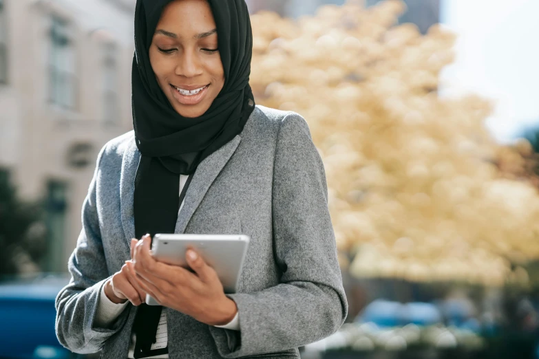 a woman in a hijab using a tablet computer, by Carey Morris, trending on unsplash, hurufiyya, woman in business suit, wearing jacket and skirt, thumbnail, a handsome