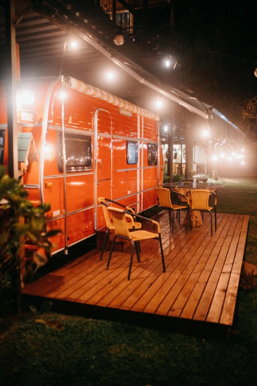an orange food truck sitting on top of a wooden deck, cosy vibes, nightcafe, caravan, brown