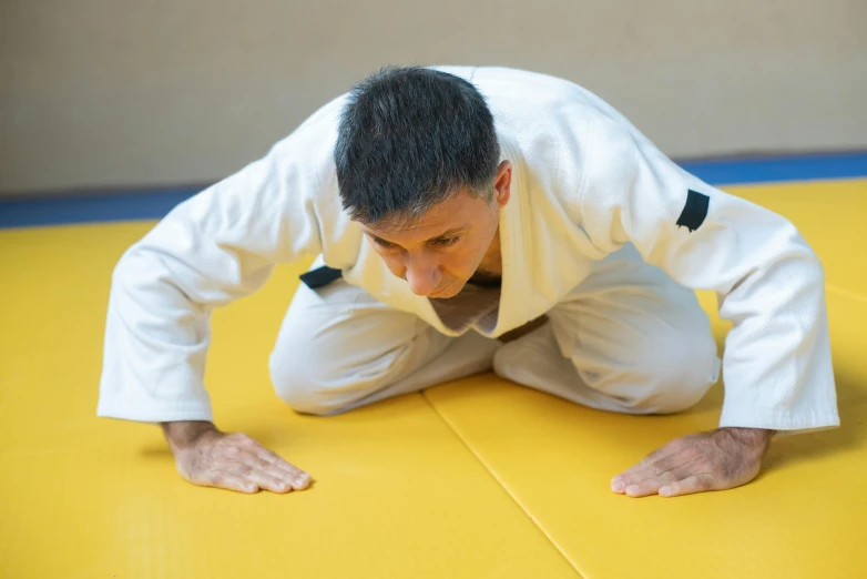 a man sitting on top of a yellow mat, aggressive stance, grading, profile image, close-up photograph