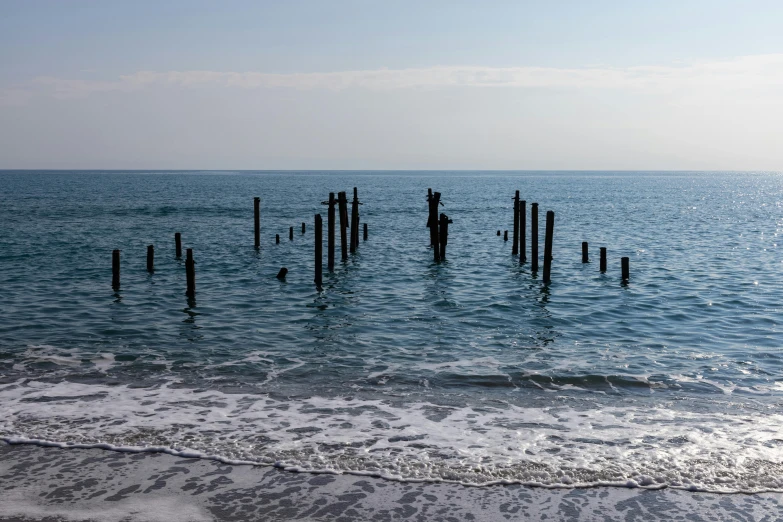 a body of water with poles sticking out of it, inspired by Thomas Struth, unsplash, black sea, medium format, ruined, wooden supports