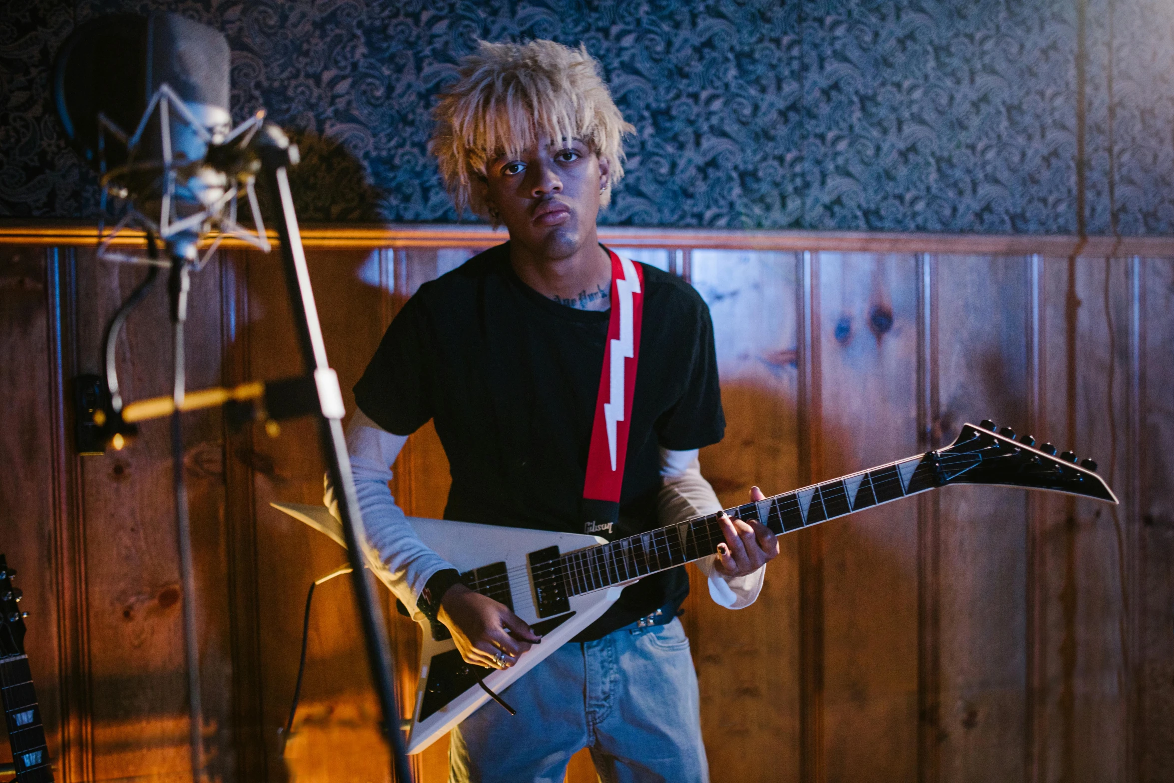 a man holding a guitar in front of a microphone, an album cover, pexels, realism, xxxtentacion, short blonde afro, in his basement studio, crazy eyes wide open