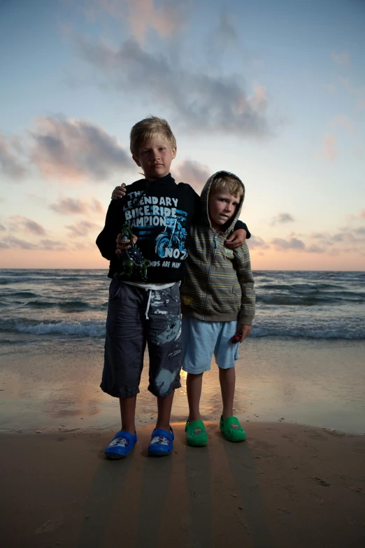 a couple of kids standing on top of a sandy beach, by Michael Goldberg, slide show, heartbreaking, boys, multicoloured