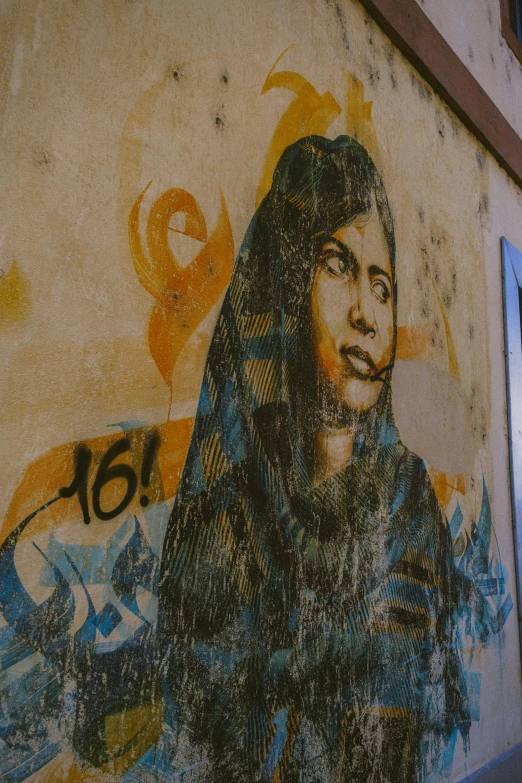 a painting of a woman on the side of a building, by Naza, pexels contest winner, street art, tuareg, historical photo, agrigento, revolutionary