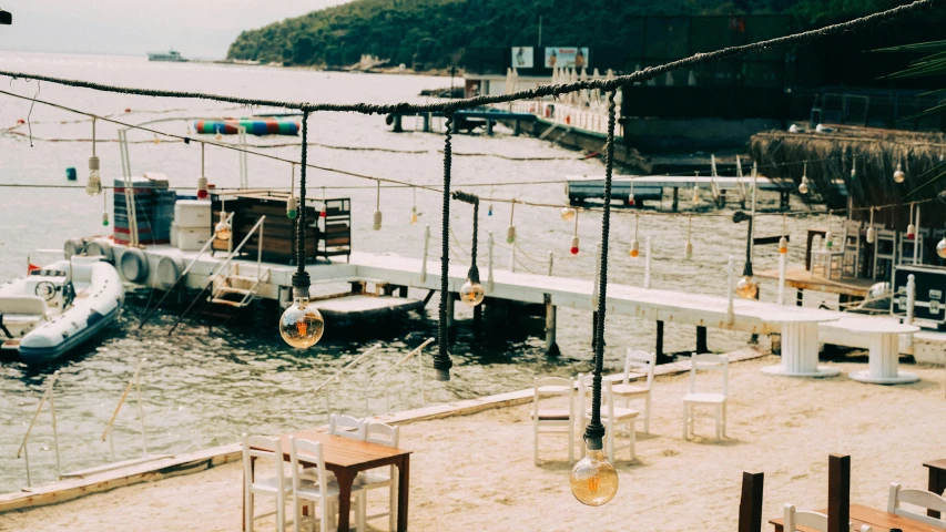 a boat that is sitting in the water, by Elsa Bleda, pexels contest winner, beach bar, hanging lanterns, instagram story, 1990's photo