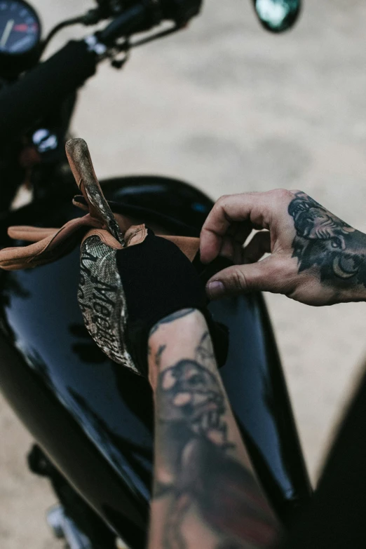 a close up of a person holding a knife on a motorcycle, a tattoo, by Daniel Seghers, trending on pexels, bandanas, leather and suede, australian, curated collection