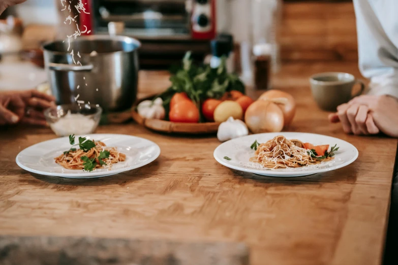 a close up of two plates of food on a table, pexels contest winner, cooking it up, italian, on wooden table, full body image