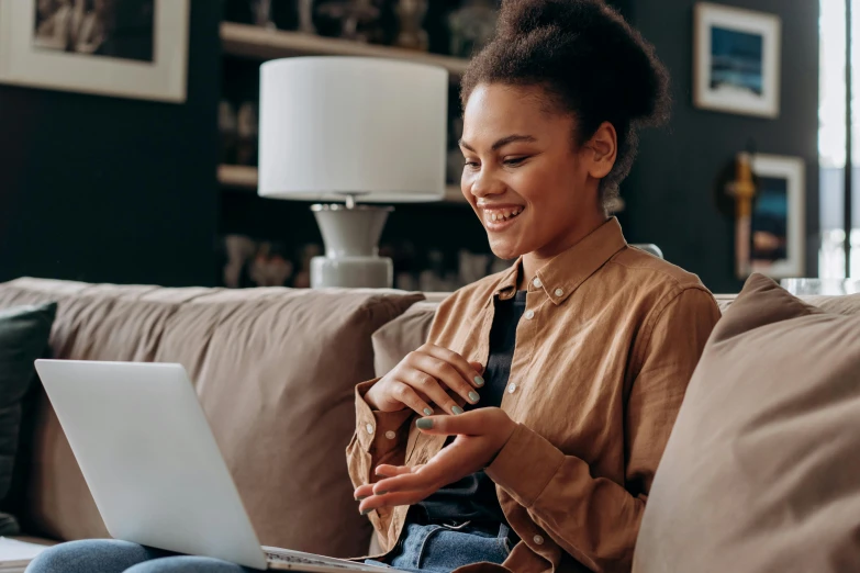 a woman sitting on a couch using a laptop, a portrait, trending on pexels, happening, smiling playfully, avatar image, brown, great details