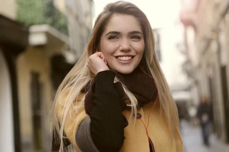 a woman walking down a street talking on a cell phone, trending on pexels, brown-blond-hair pretty face, hailee steinfeld, happy grin, earbuds jewelry