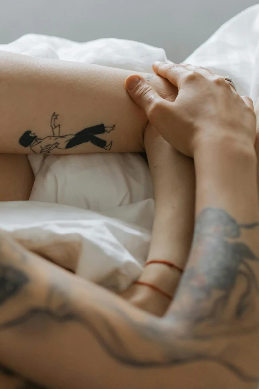 a woman laying in bed with a tattoo on her arm, trending on pexels, visual art, two men hugging, multiple limbs, hugging her knees, simple art