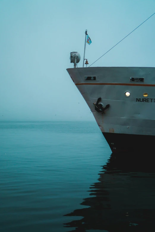 a large white boat floating on top of a body of water, a photo, by Christen Dalsgaard, pexels contest winner, romanticism, cyan fog, stern face, utilitarian cargo ship, before dawn