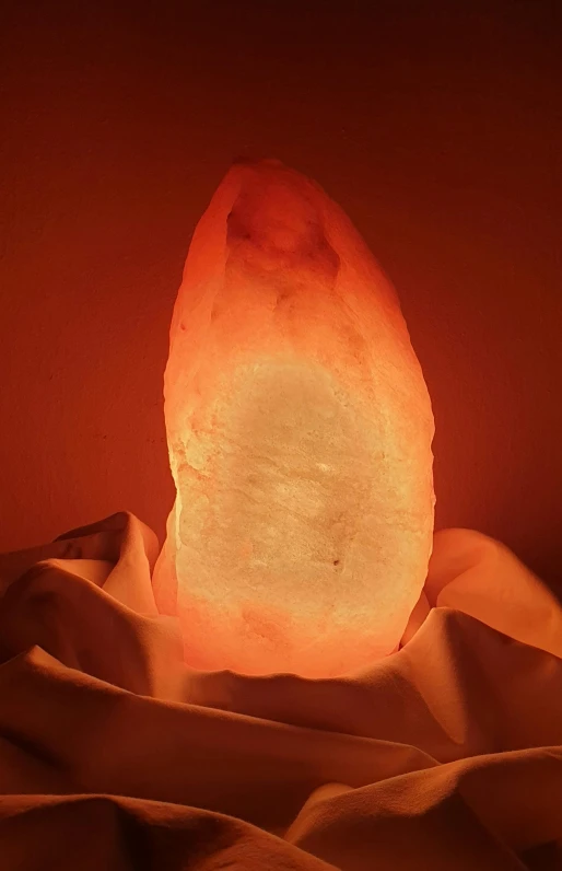 a large rock sitting on top of a bed, red glowing skin, light cone, soft lightening, made of glowing wax and ceramic