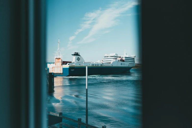 a large boat sitting on top of a body of water, a tilt shift photo, pexels contest winner, happening, seen through a window, shipping docks, scandinavian, blue and green water