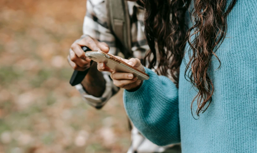 a close up of a person holding a cell phone, by Niko Henrichon, trending on pexels, plein air, teenage girl, hunting, collaboration, autumnal