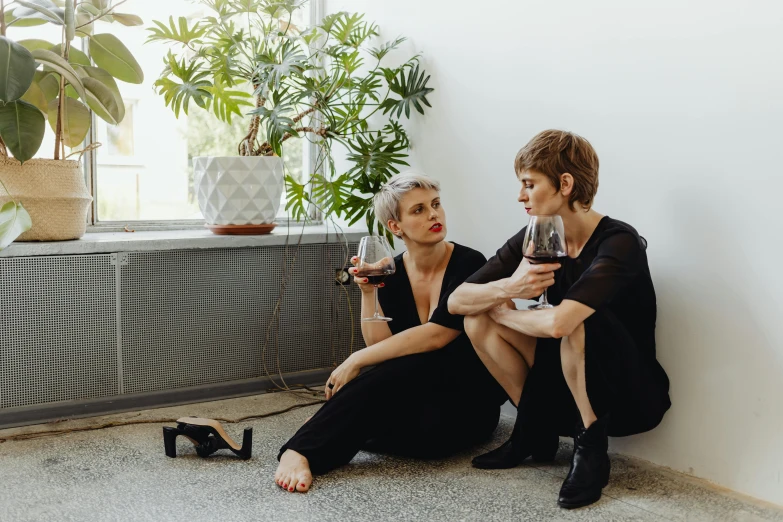 two women sitting next to each other holding wine glasses, by Liza Donnelly, purism, sitting on the floor, profile image, queer woman, aussie baristas