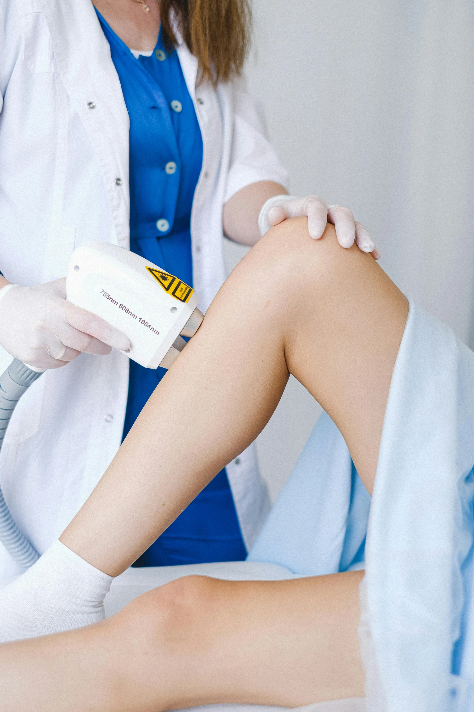 a woman getting a laser treatment on her leg, trending on reddit, wearing lab coat and a blouse, thumbnail, background image, brown