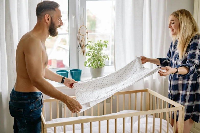 a man and a woman standing in front of a crib, by Julia Pishtar, pexels contest winner, white sheets, boys, as well as the handyboy, flat