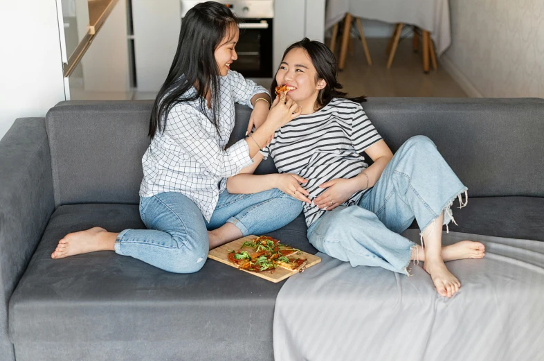 two women sitting on a couch eating pizza, by Julia Pishtar, pexels contest winner, asian male, third trimester, grey, healthy