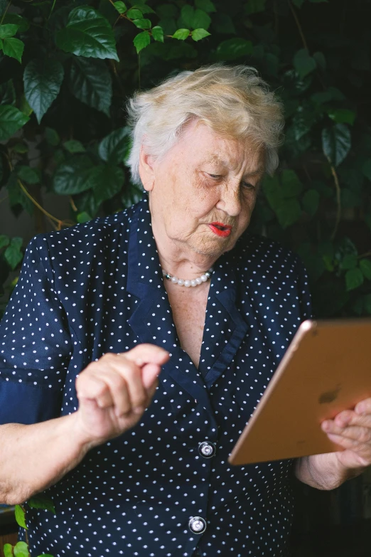 an older woman is using a tablet computer, an album cover, unsplash, exasperated, dots, high quality photo, basil gogos