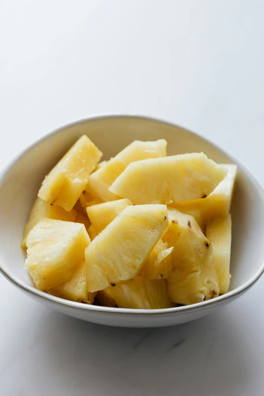 a bowl filled with sliced pineapples on top of a table, square, polished, mild, organics