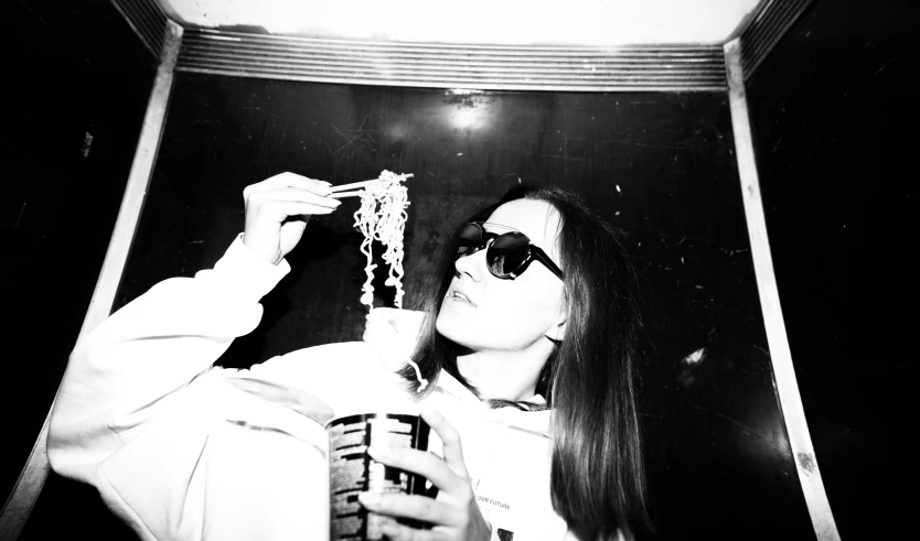 a black and white photo of a woman eating spaghetti, purism, wearing shades, rice, with seaweed, bella poarch