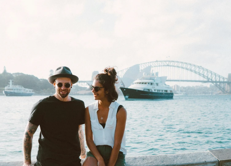 a man and a woman sitting next to a body of water, a picture, harbour, portrait featured on unsplash, sydney mortimer laurence, tourist