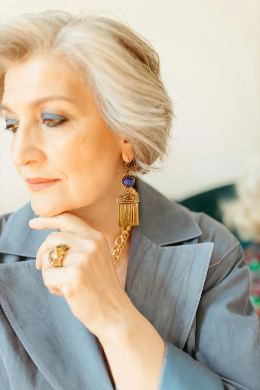 a close up of a person holding a cell phone, an album cover, by Winona Nelson, renaissance, elaborate earrings, portrait 6 0 - year - old woman, golden blue outfit, marie - gabrielle capet style