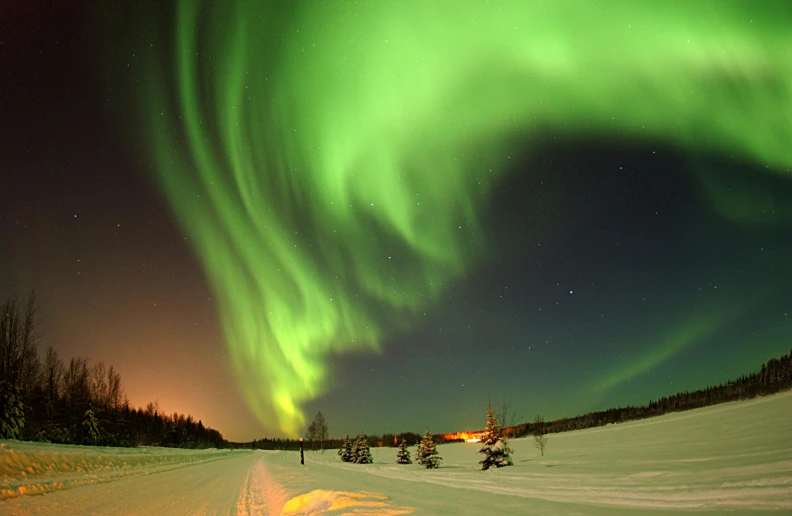 a group of people riding skis down a snow covered slope, aurora borealis in the sky, eero aarnio, green lights, electric cats that fly over ice