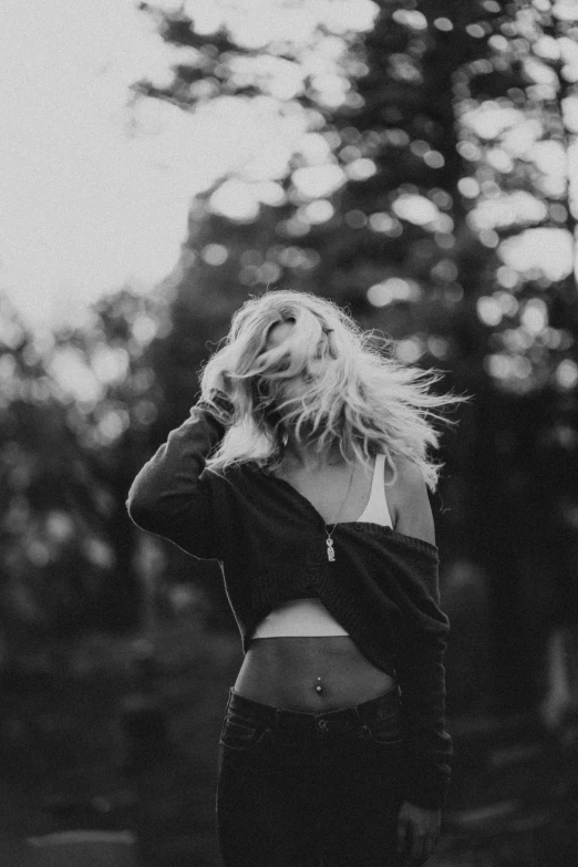 a woman standing in the middle of a forest, a black and white photo, inspired by Elsa Bleda, trending on pexels, golden hair blowing the wind, wearing torn clothes, at a park, highly [ detailed ]