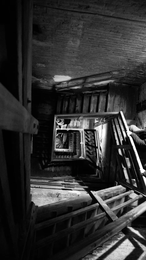 a black and white photo of a man sitting on a chair, a black and white photo, inspired by André Kertész, dada, look down a cellar staircase, holga 120n, under repairs, an escape room in a small