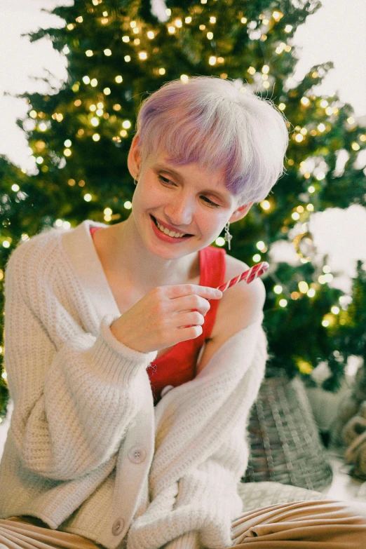 a woman sitting in front of a christmas tree, inspired by Winona Nelson, pexels contest winner, short platinum hair tomboy, candy pastel, male ulzzang, smiling sweetly