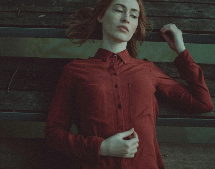 a woman standing in front of a wooden bench, an album cover, inspired by Elsa Bleda, pexels contest winner, antipodeans, redhead woman, red clothes, grainy movie still, scary pose