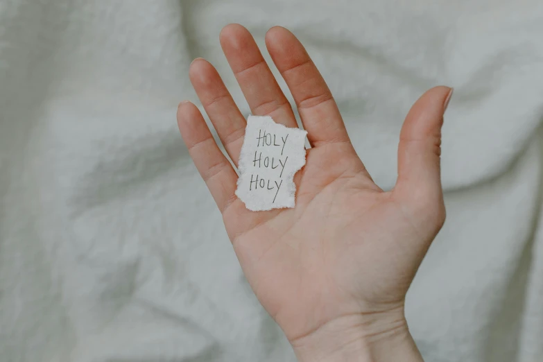 a hand holding a piece of paper with writing on it, pexels, holy themed, hey, soft skin, full shot photograph