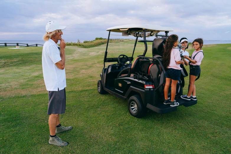 a man talking on a cell phone next to a golf cart, views to the ocean, avatar image, group photo, family friendly