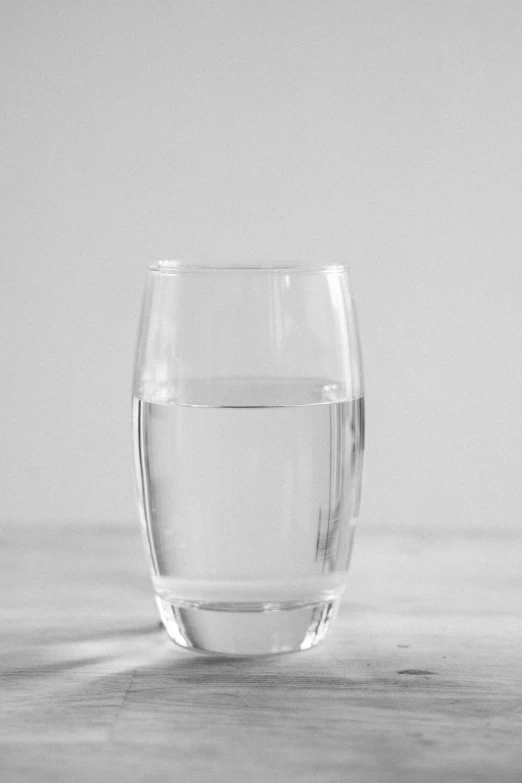 a glass of water sitting on top of a table, on a gray background, uploaded, made of water, with a white background