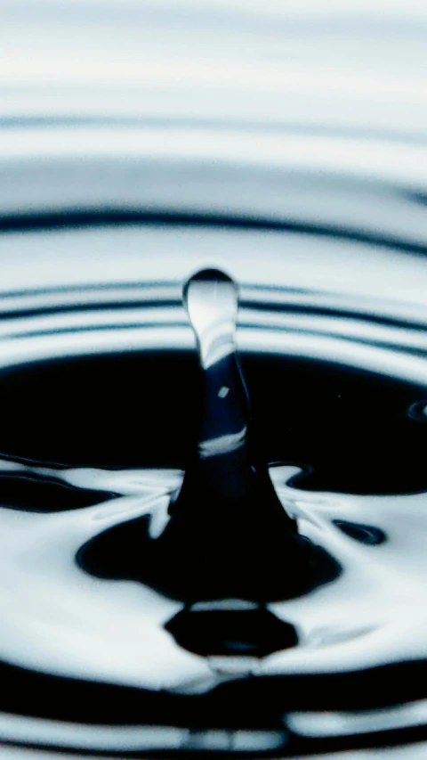 a close up of a drop of water, an album cover, inspired by Lucio Fontana, purism, blacks and blues, cooking oil, stockphoto, raven black