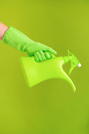 a person in green gloves holding a green watering can, a picture, shutterstock, plasticien, spray, solid background, indoor picture, sprays