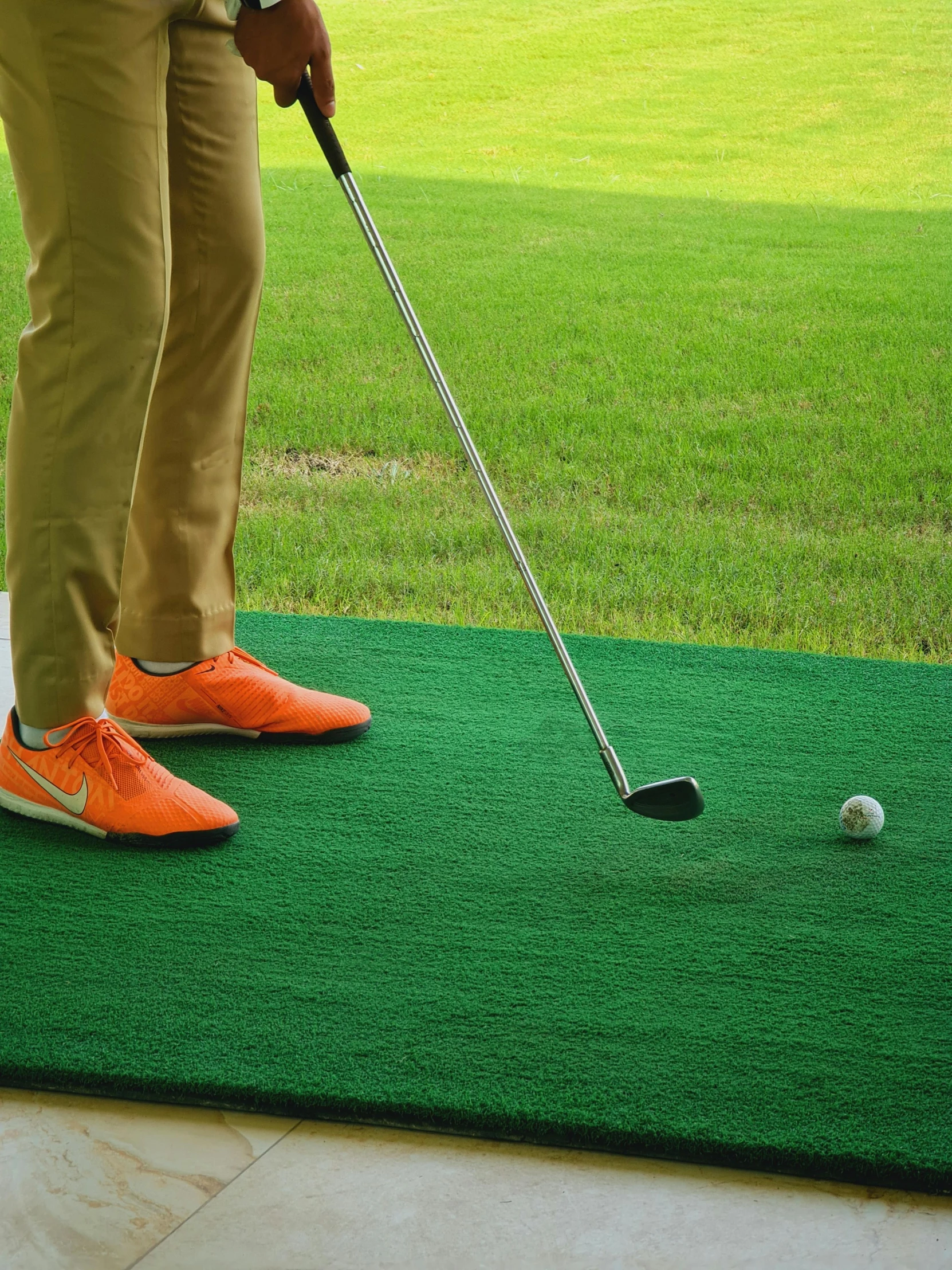 a man holding a golf club on top of a green mat, standing on 2 feet, rugs, promotional, shot from 5 0 feet distance