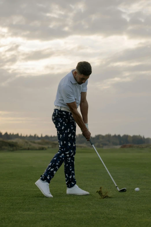 a man standing on top of a green field holding a golf club, stripey pants, patterns, mid action swing, liam brazier