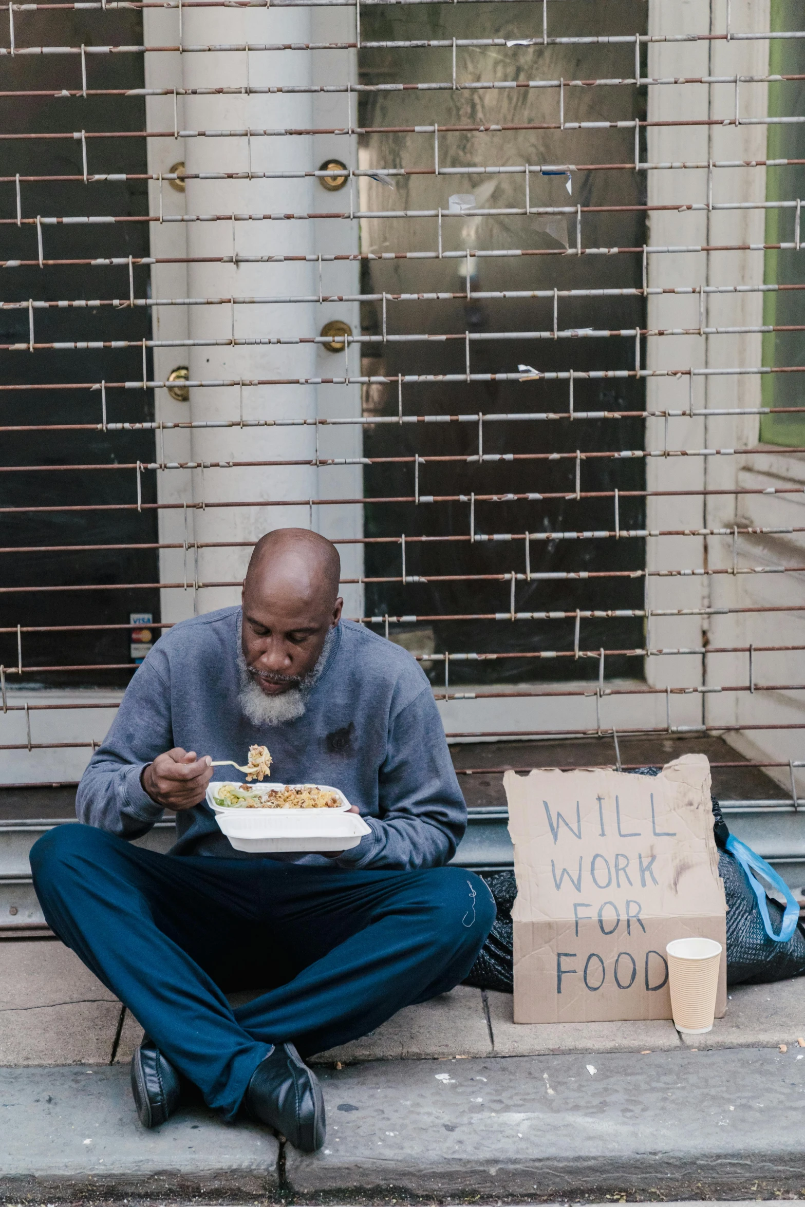 a man sitting on the sidewalk eating food, by William Berra, pexels contest winner, renaissance, samuel l jackson, a bald, someone in home sits in bed, kneeling