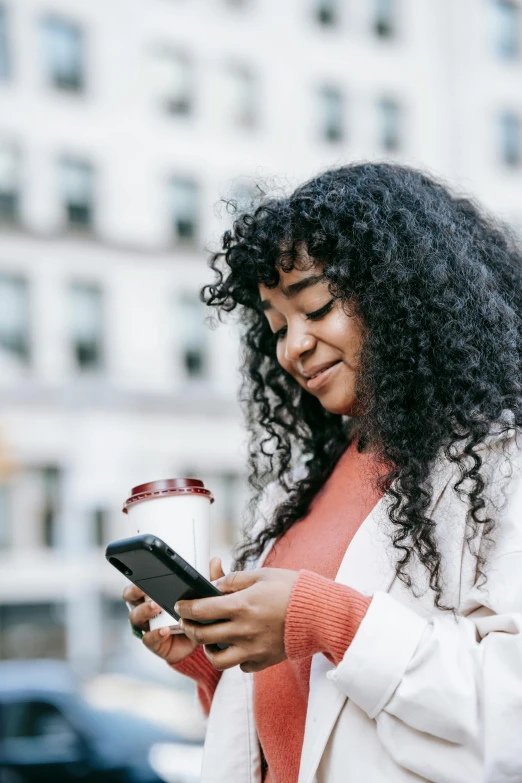 a woman holding a cup of coffee and looking at her cell phone, trending on pexels, happening, black curly hair, square, ilustration, outside