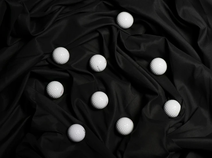 a bunch of golf balls on a black cloth, an album cover, by irakli nadar, unsplash, surrealism, white cloth, fabrics, playful composition canon, black jersey