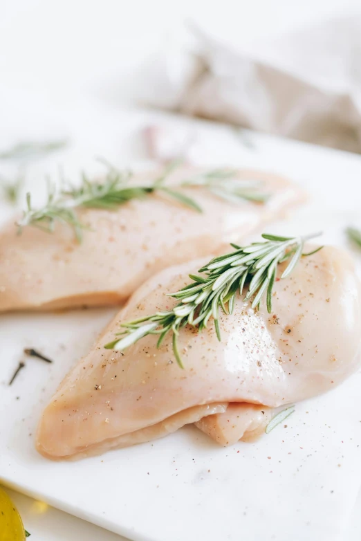 two pieces of chicken sitting on top of a white plate, a picture, trending on pexels, renaissance, herbs, covered breasts, unfinished, 6 pack